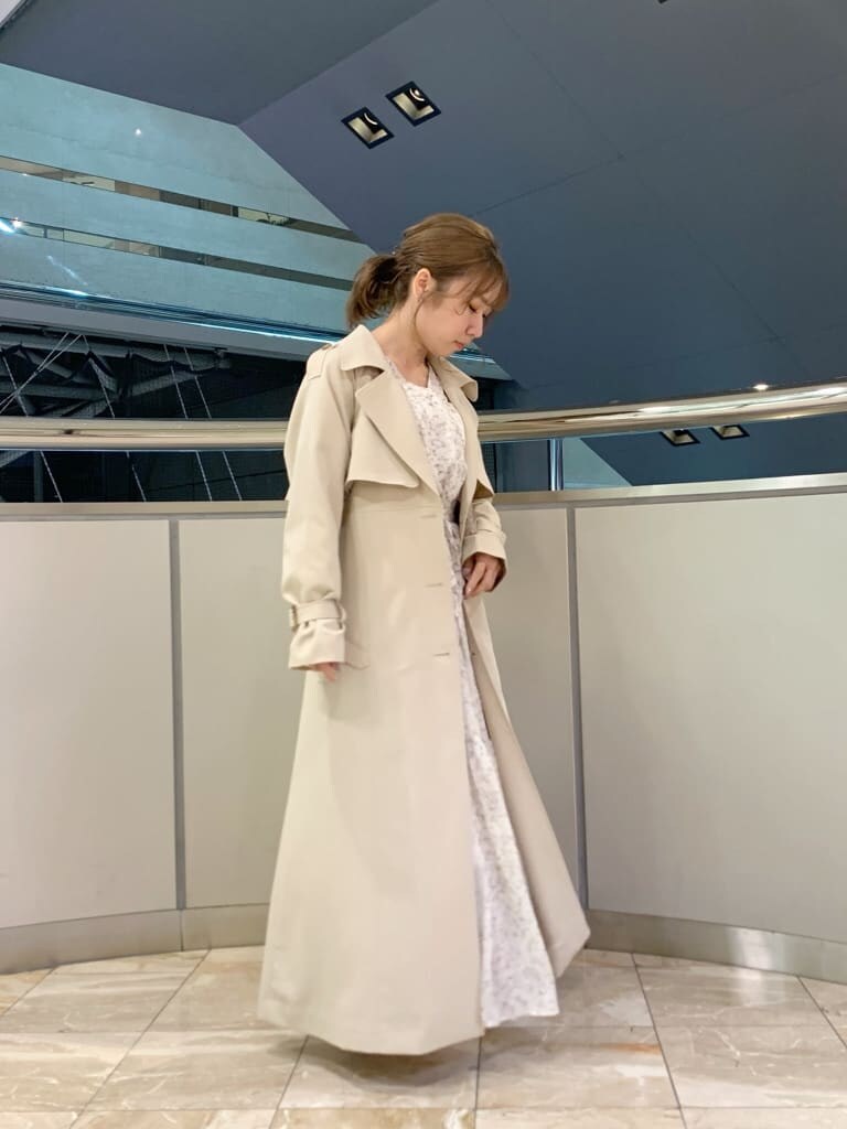 ベージュ系のトレンチコート、オレンジ系のワンピース、ホワイト系のパンプスを着用したレディースの冬コーディネートの6枚目の写真