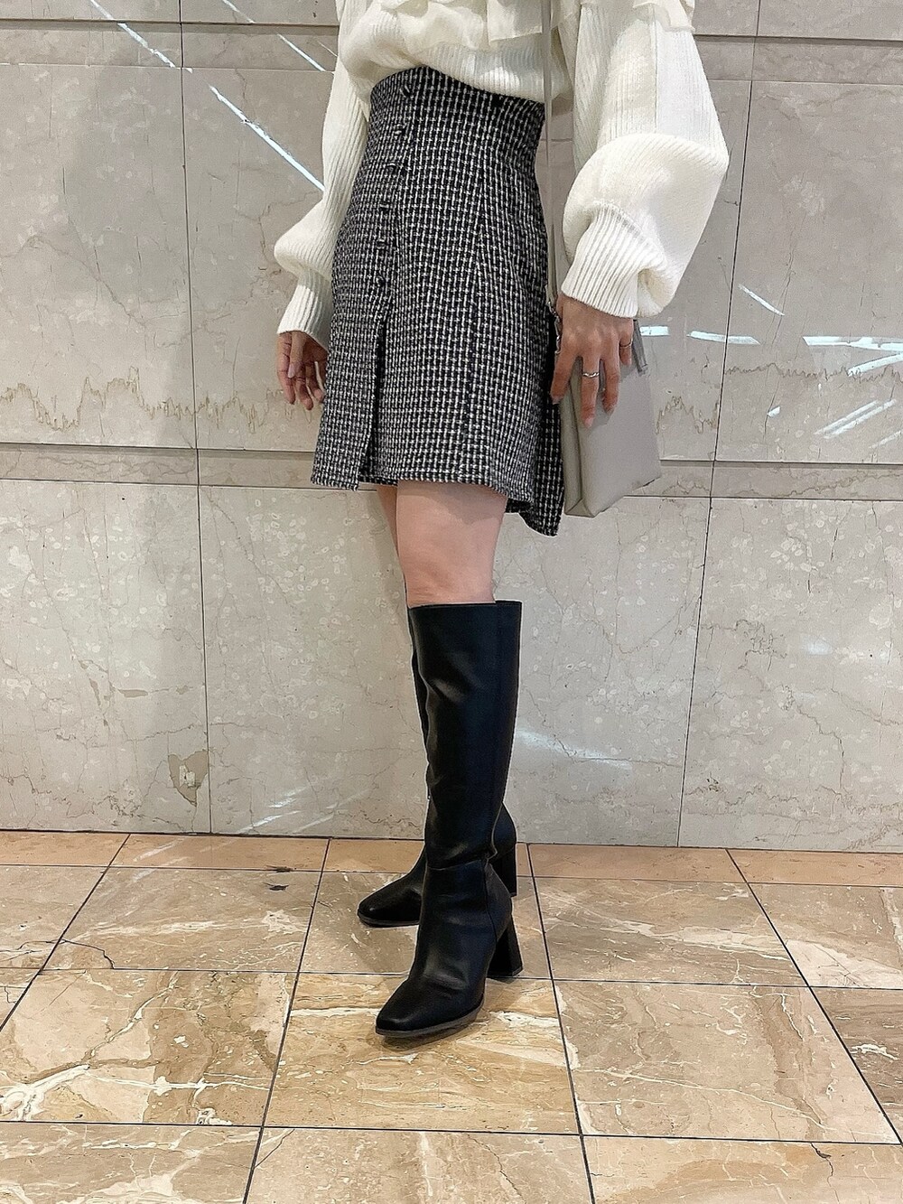 ホワイト系のニット/セーター、ブルー系のスカート、ブラック系のブーツを着用したレディースの秋コーディネートの9枚目の写真