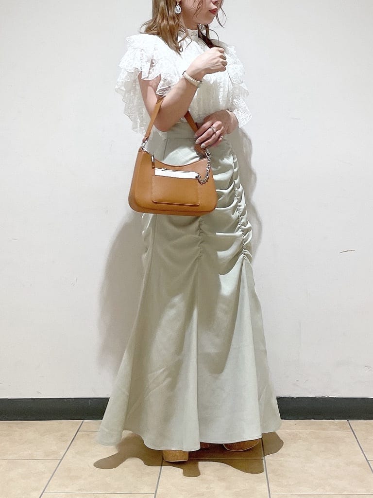 グリーン系のスカート、ブラウン系のハンドバッグ、ホワイト系のシャツ/ブラウスを着用したレディースの夏コーディネートの2枚目の写真