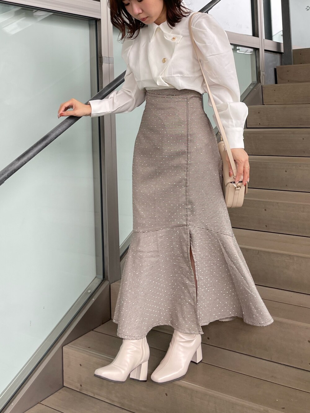 ホワイト系のシャツ/ブラウス、ブラウン系のスカート、ベージュ系のブーツを着用したレディースの秋コーディネートの2枚目の写真