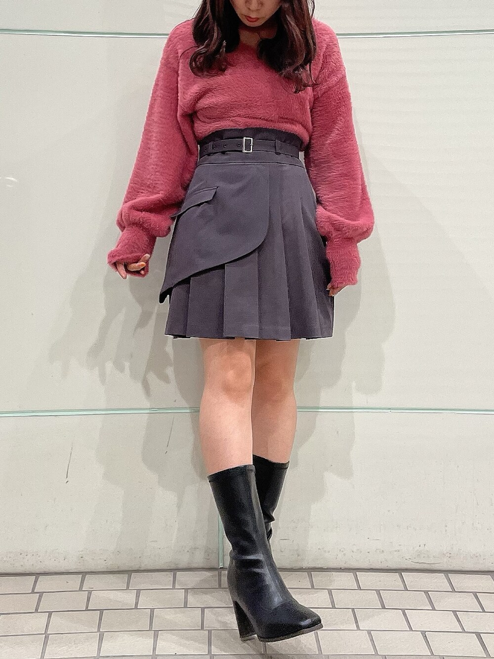 ピンク系のニット/セーター、グレー系のスカート、ブラック系のブーツを着用したレディースの秋コーディネートの5枚目の写真
