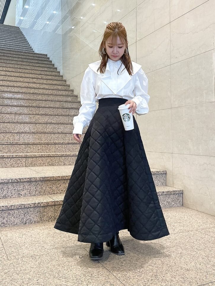 ホワイト系のシャツ/ブラウス、ブラック系のブーツ、ブラック系のスカートを着用したレディースの秋コーディネートの2枚目の写真