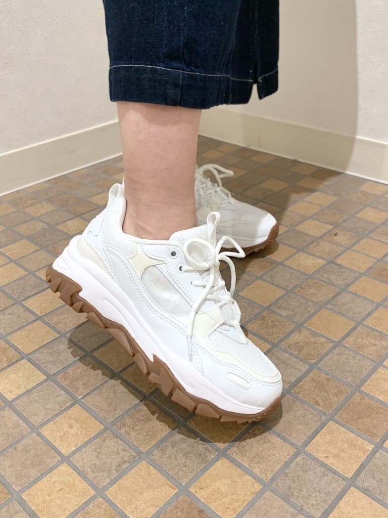 ホワイト系のスニーカー、ブルー系のジャンパースカート、グリーン系のニット/セーターを着用したレディースの春コーディネートの5枚目の写真