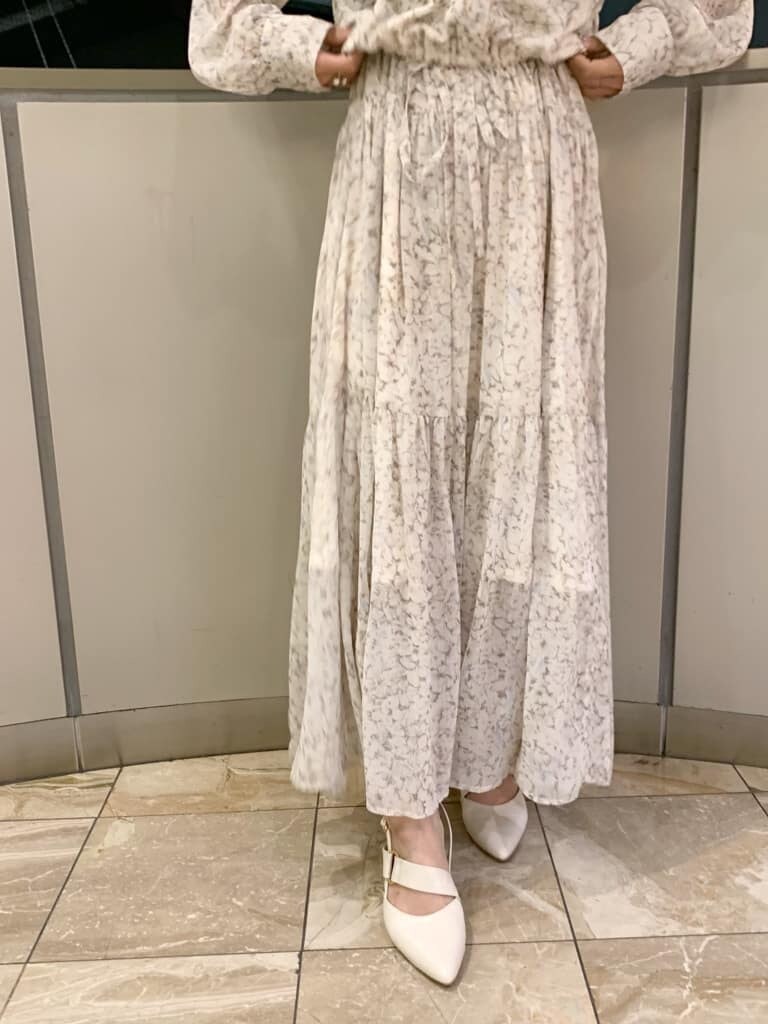 ベージュ系のトレンチコート、オレンジ系のワンピース、ホワイト系のパンプスを着用したレディースの冬コーディネートの5枚目の写真