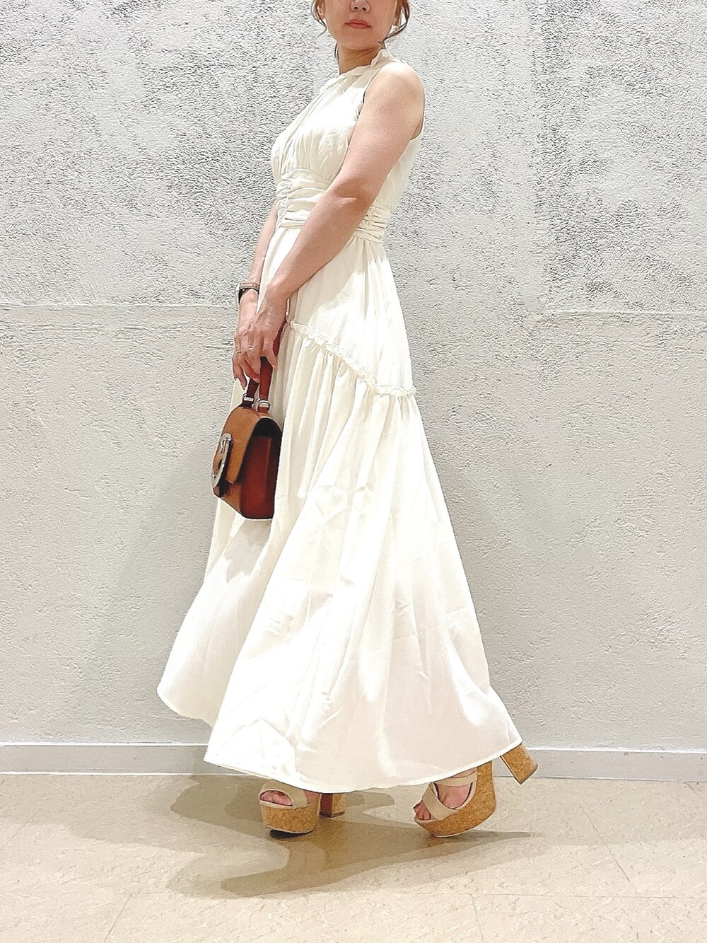 イエロー系のハンドバッグ、ホワイト系のサンダル、ホワイト系のワンピースを着用したレディースの夏コーディネートの4枚目の写真