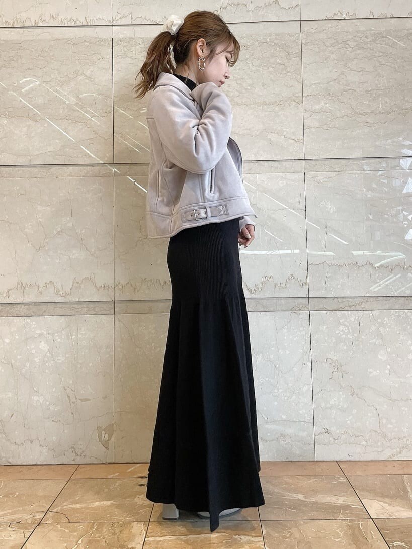 パープル系のライダースジャケット、ベージュ系のブーツ、ブラック系のワンピースを着用したレディースの秋コーディネートの2枚目の写真