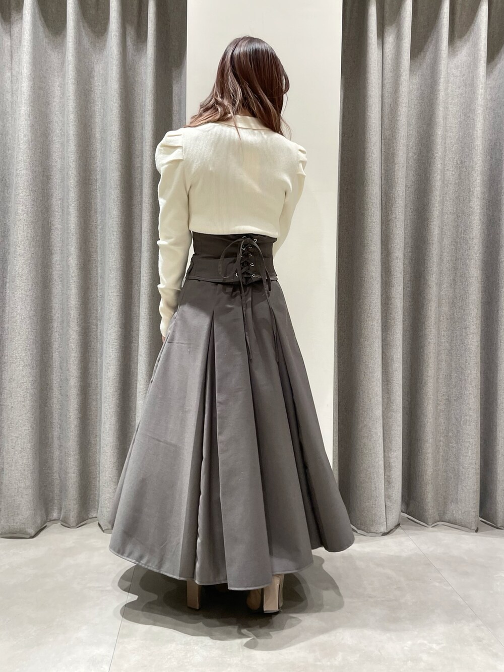 ホワイト系のニット/セーター、グレー系のスカート、ベージュ系のブーツを着用したレディースの冬コーディネートの3枚目の写真