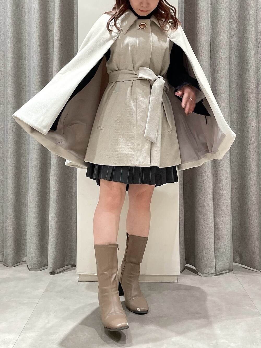 ホワイト系のポンチョ、ブラック系のニット/セーター、グレー系のスカートを着用したレディースの冬コーディネートの4枚目の写真