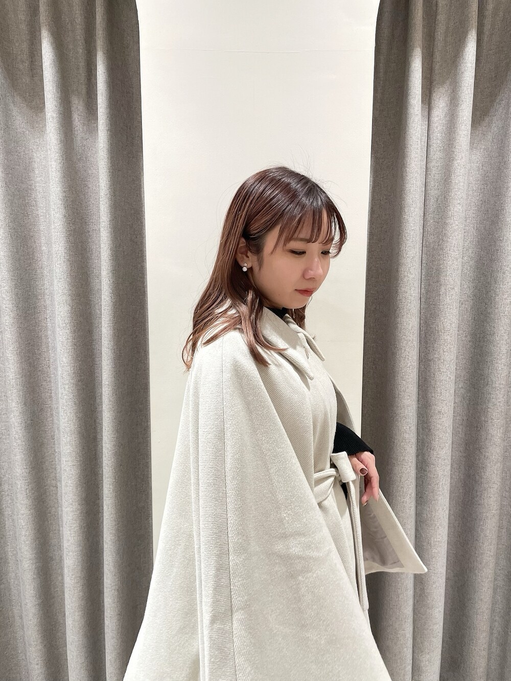 ホワイト系のポンチョ、ブラック系のニット/セーター、グレー系のスカートを着用したレディースの冬コーディネートの7枚目の写真