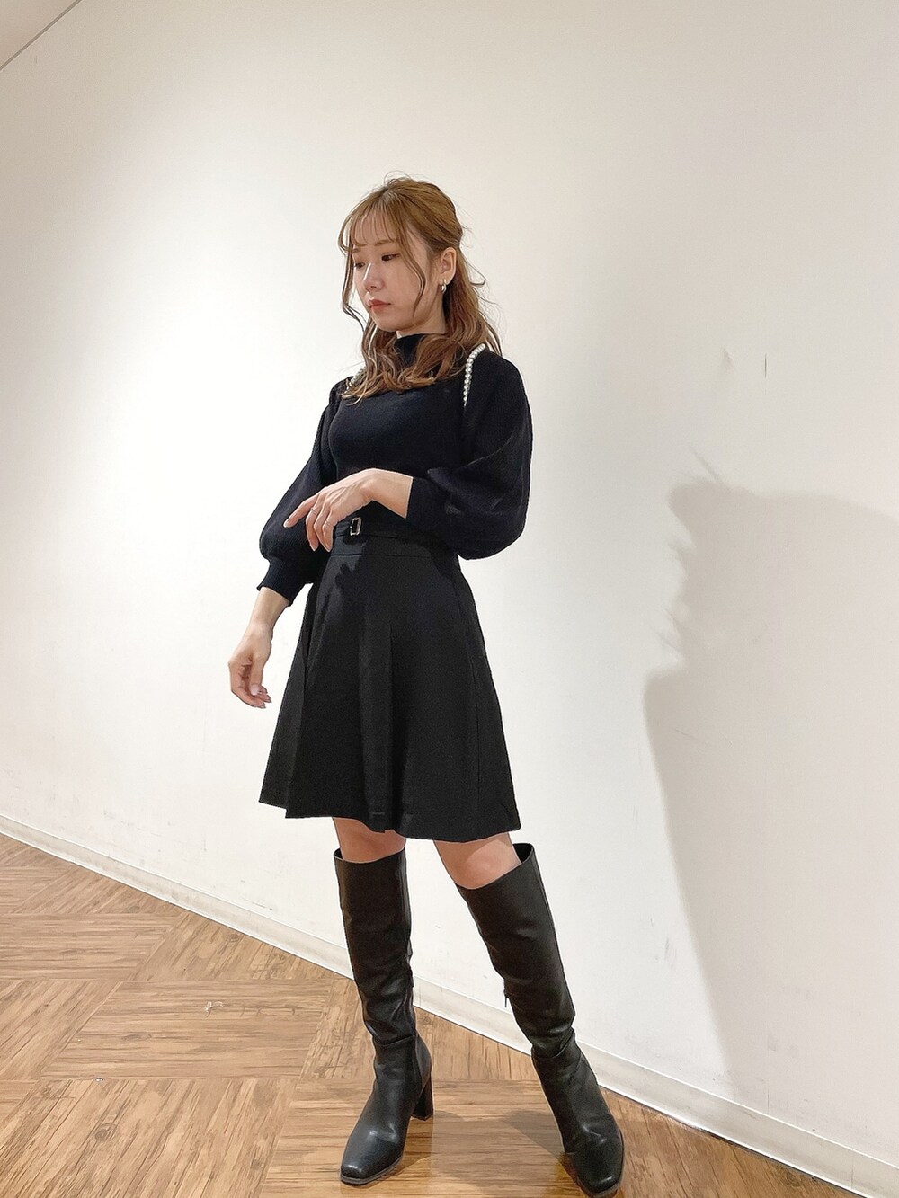ブラック系のスカート、ブラック系のニット/セーター、ブラック系のブーツを着用したレディースの冬コーディネートの2枚目の写真