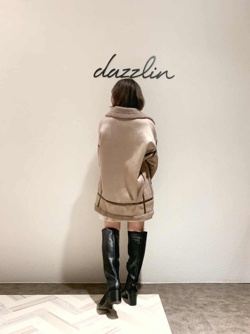 ベージュ系のブルゾン、ベージュ系のスカート、ブラック系のブーツを着用したレディースの秋コーディネートの4枚目の写真