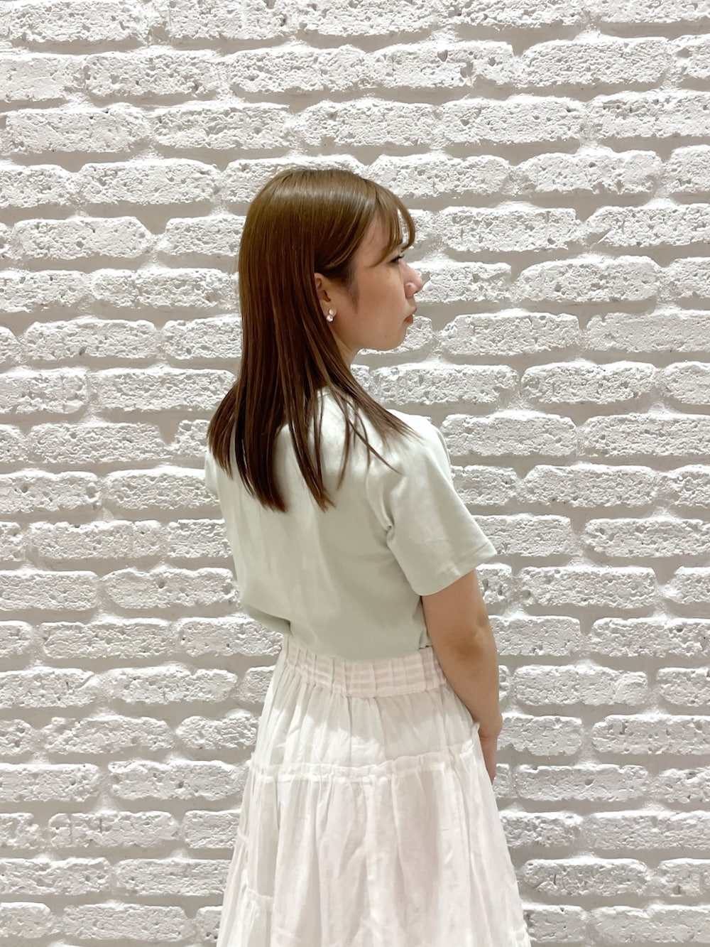 グリーン系のTシャツ/カットソー、ホワイト系のスカート、シルバー系のパンプスを着用したレディースの春コーディネートの6枚目の写真