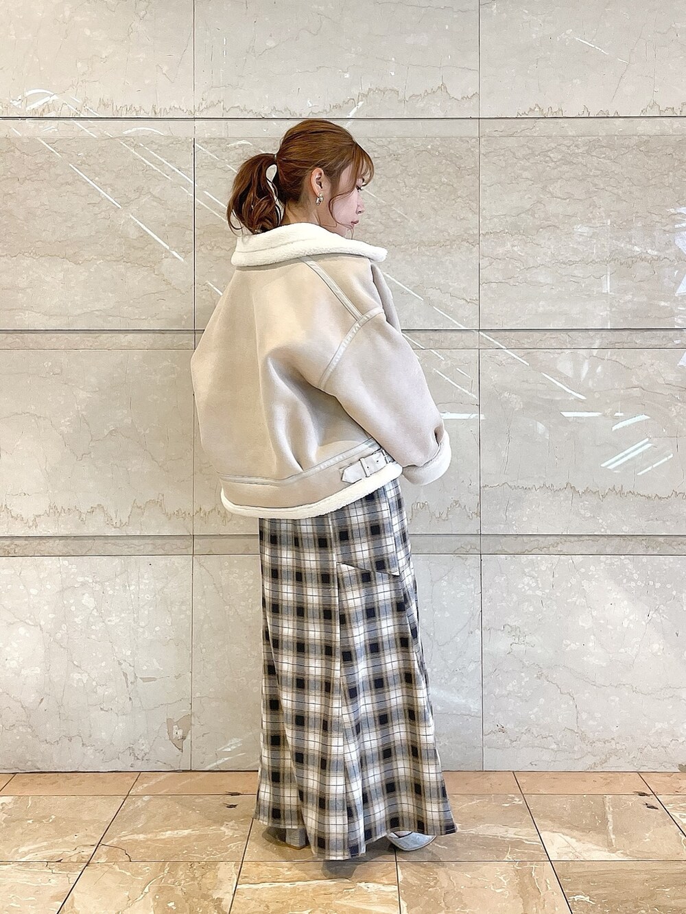 ホワイト系のブルゾン、イエロー系のワンピース、グレー系のパンプスを着用したレディースの冬コーディネートの3枚目の写真