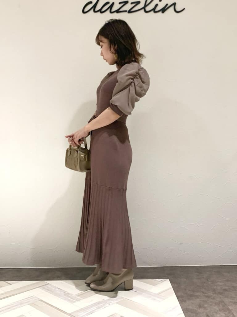 ブラウン系のワンピース、グレー系のトレンチコート、ベージュ系のハンドバッグを着用したレディースの秋コーディネートの4枚目の写真