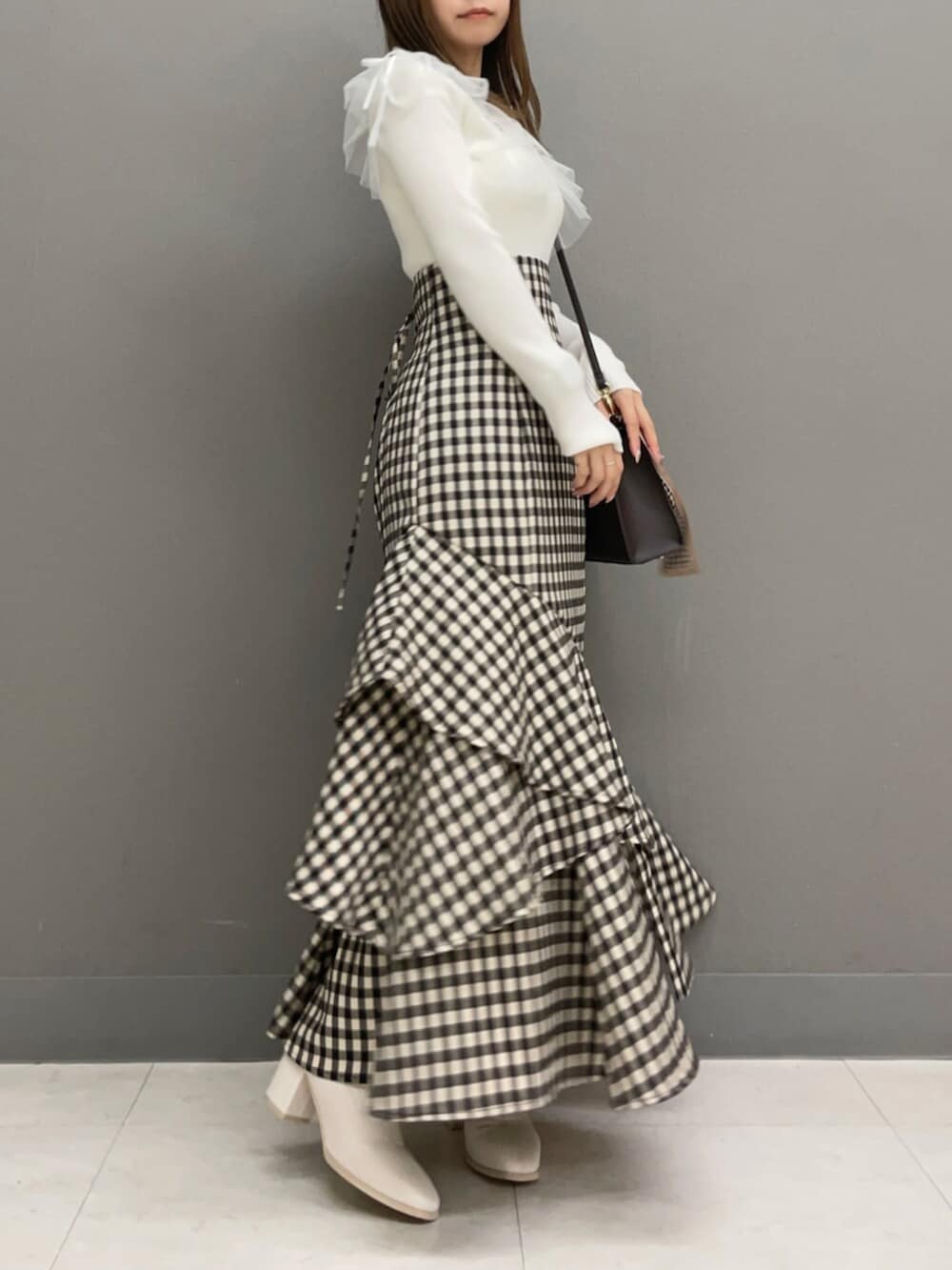 ブラウン系のショルダーバッグ、ホワイト系のブーツ、ホワイト系のニット/セーターを着用したレディースの秋コーディネートの2枚目の写真