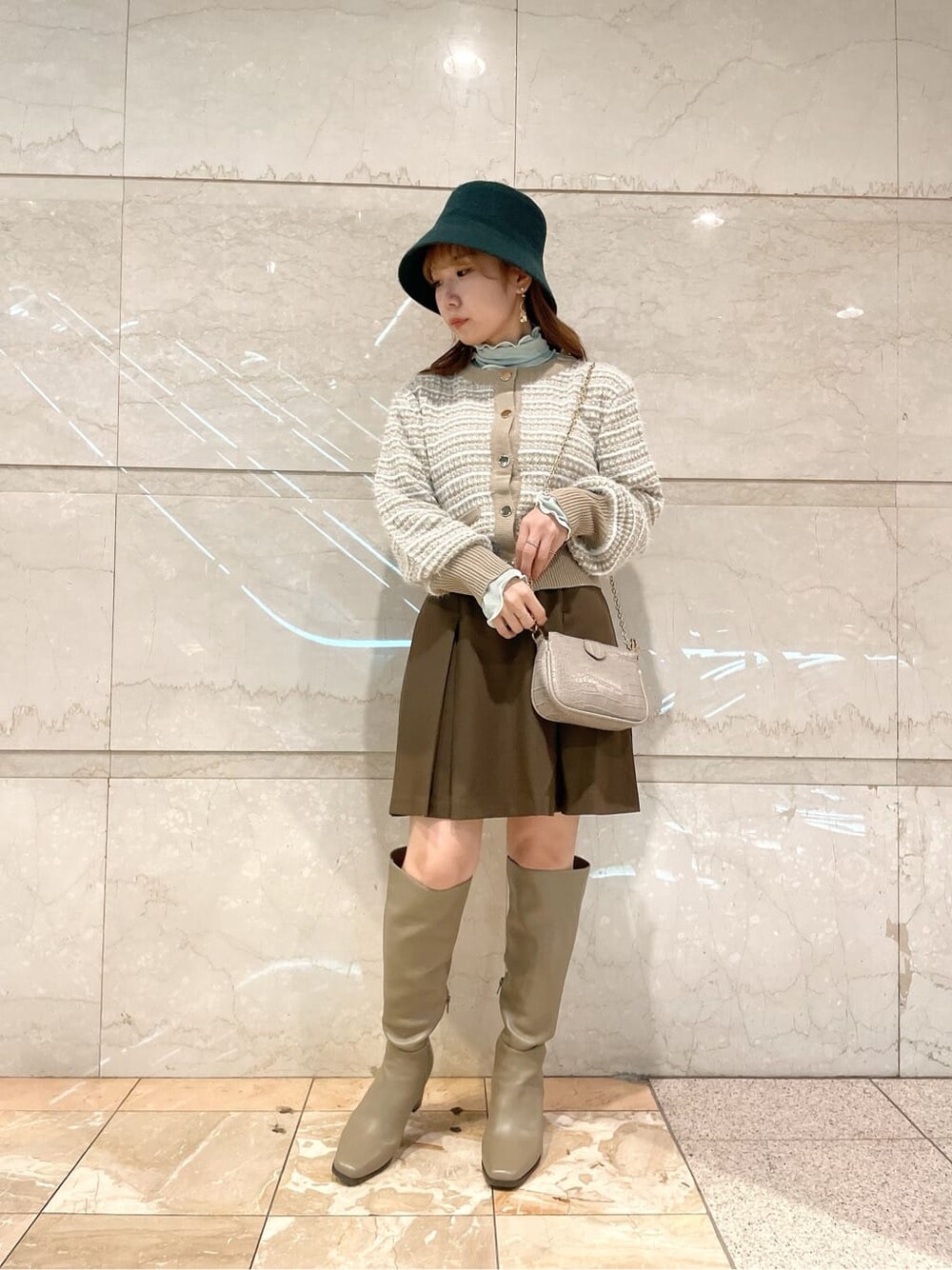 ブラウン系のスカート、ベージュ系のブーツ、ベージュ系のカーディガン/ボレロを着用したレディースの秋コーディネートの2枚目の写真
