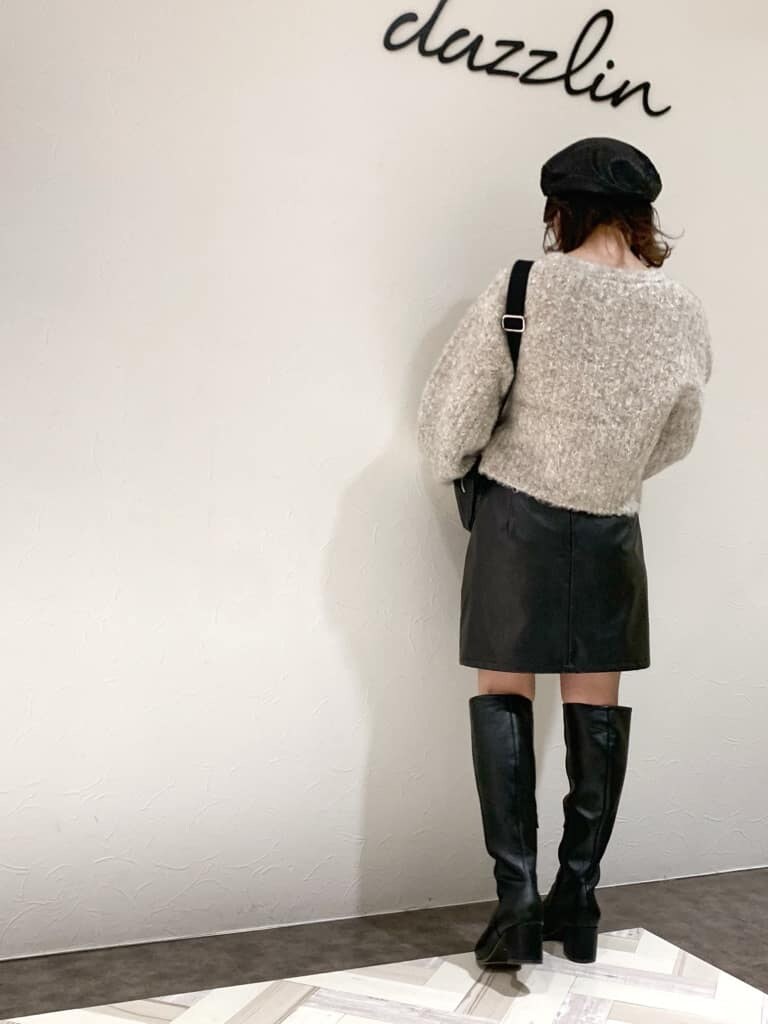 ブラック系のスカート、ブラック系のブーツ、ベージュ系のニット/セーターを着用したレディースの秋コーディネートの4枚目の写真