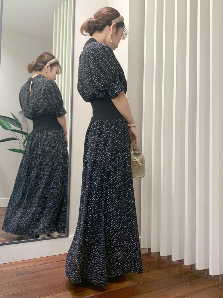 ベージュ系のブーツ、ベージュ系のハンドバッグ、ブラック系のワンピースを着用したレディースの秋コーディネートの4枚目の写真