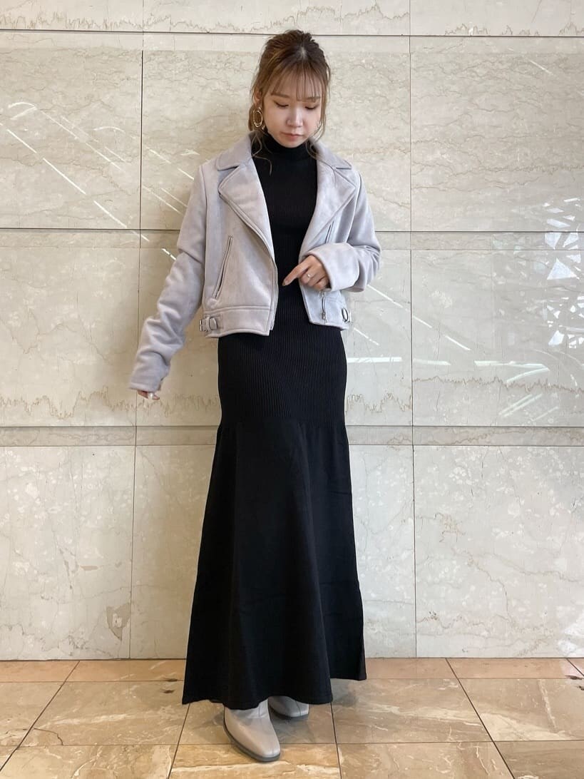 パープル系のライダースジャケット、ベージュ系のブーツ、ブラック系のワンピースを着用したレディースの秋コーディネートの3枚目の写真