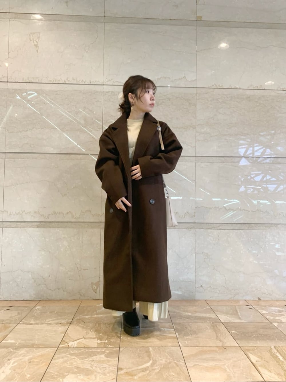 ブラック系のブーツ、ブラウン系のチェスターコート、ベージュ系のワンピースを着用したレディースの冬コーディネートの8枚目の写真