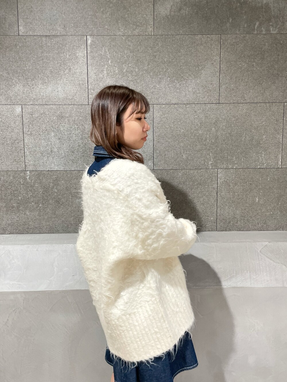 ホワイト系のカーディガン/ボレロ、ブルー系のシャツワンピース、ホワイト系のブーツを着用したレディースの冬コーディネートの6枚目の写真