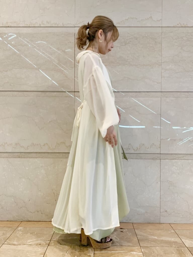 グリーン系のワンピース、ブラウン系のサンダル、ホワイト系のシャツ/ブラウスを着用したレディースの春コーディネートの8枚目の写真