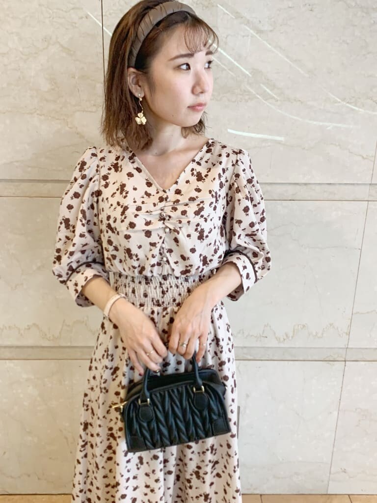 ブラック系のハンドバッグ、ブラック系のブーツ、ベージュ系のワンピースを着用したレディースの夏コーディネートの5枚目の写真