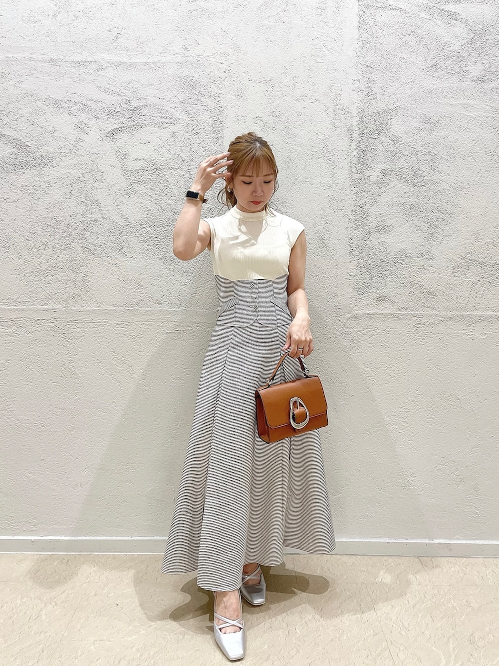 イエロー系のハンドバッグ、ホワイト系のワンピース、シルバー系のパンプスを着用したレディースの夏コーディネートの3枚目の写真