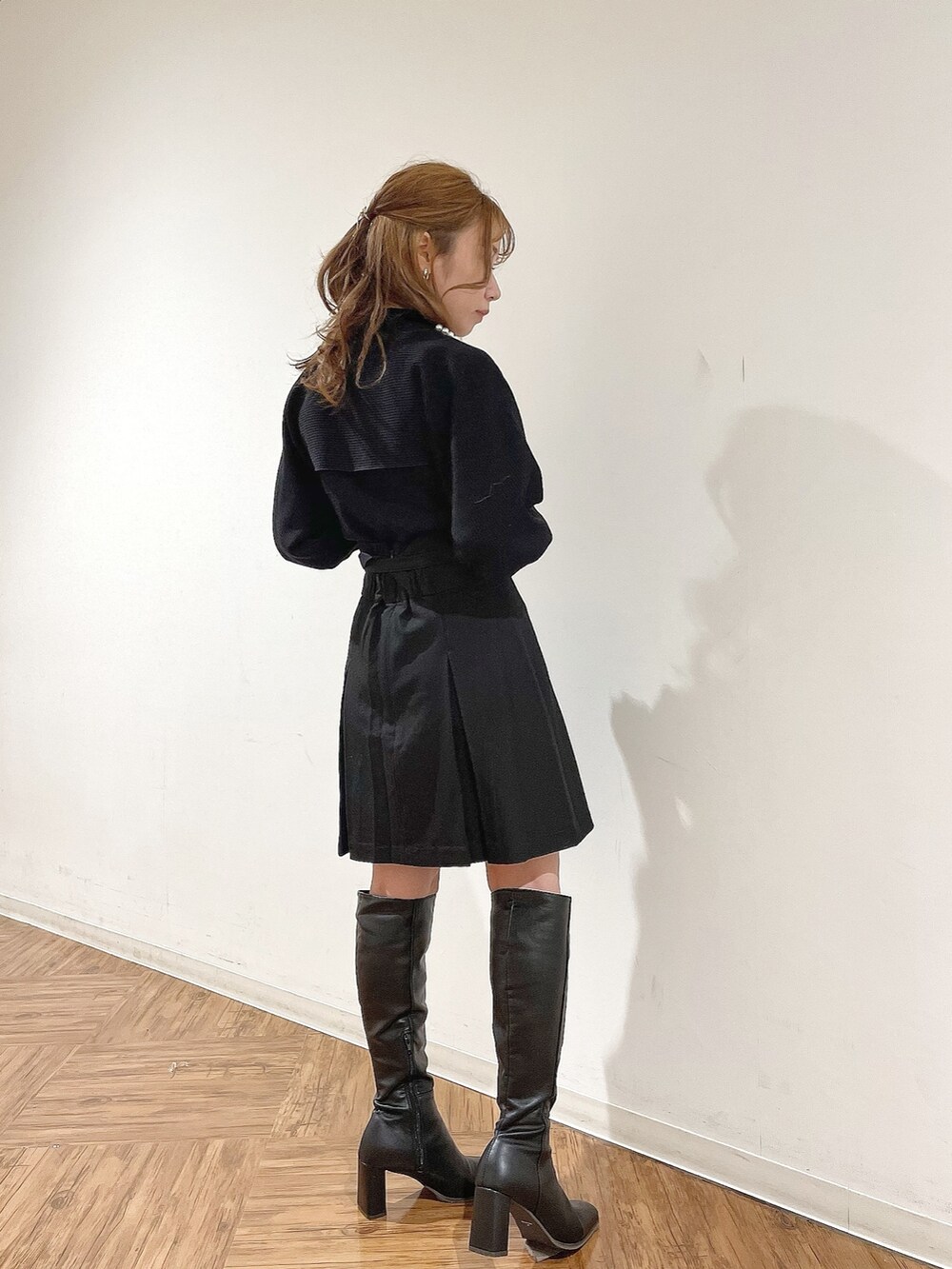 ブラック系のスカート、ブラック系のニット/セーター、ブラック系のブーツを着用したレディースの冬コーディネートの3枚目の写真
