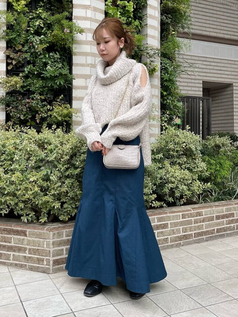 ブラック系のブーツ、ホワイト系のニット/セーター、ブルー系のスカートを着用したレディースの秋コーディネートの3枚目の写真