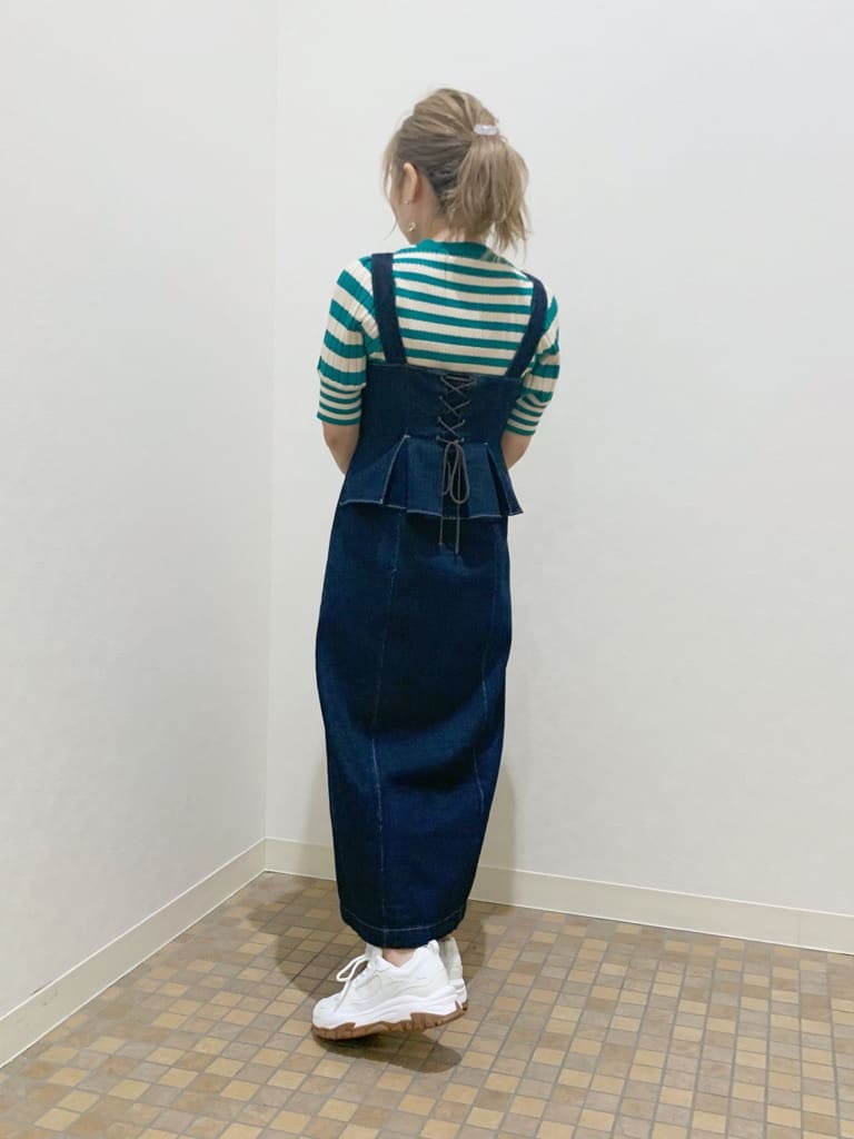 ホワイト系のスニーカー、ブルー系のジャンパースカート、グリーン系のニット/セーターを着用したレディースの春コーディネートの2枚目の写真