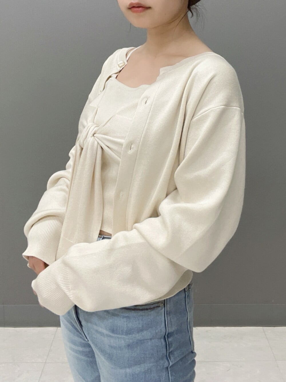 ホワイト系のキャミソール、ホワイト系のカーディガン/ボレロ、ブルー系のデニムパンツを着用したレディースの秋コーディネートの6枚目の写真