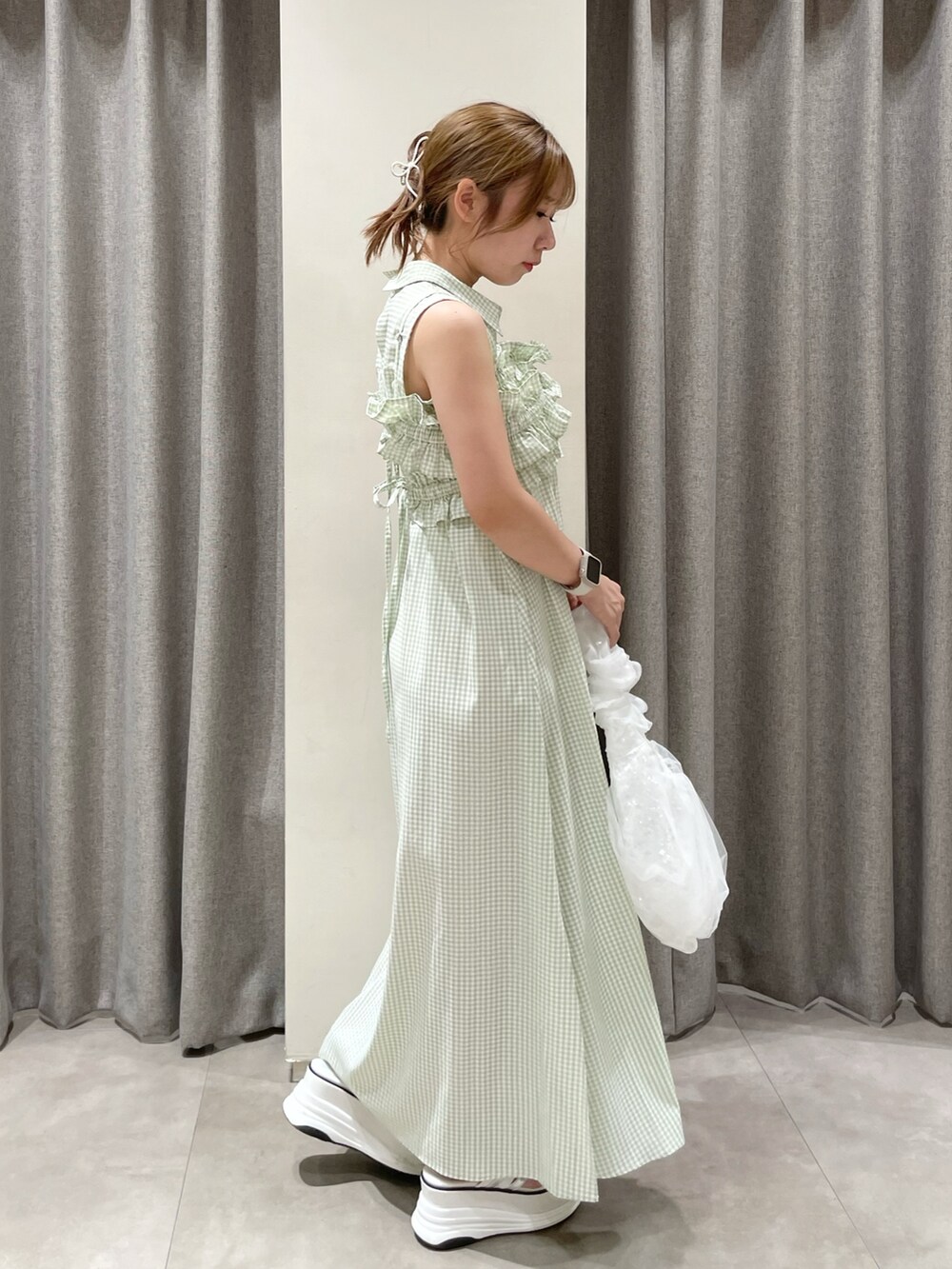 ホワイト系のハンドバッグ、ホワイト系のサンダル、グリーン系のシャツワンピースを着用したレディースの夏コーディネートの5枚目の写真