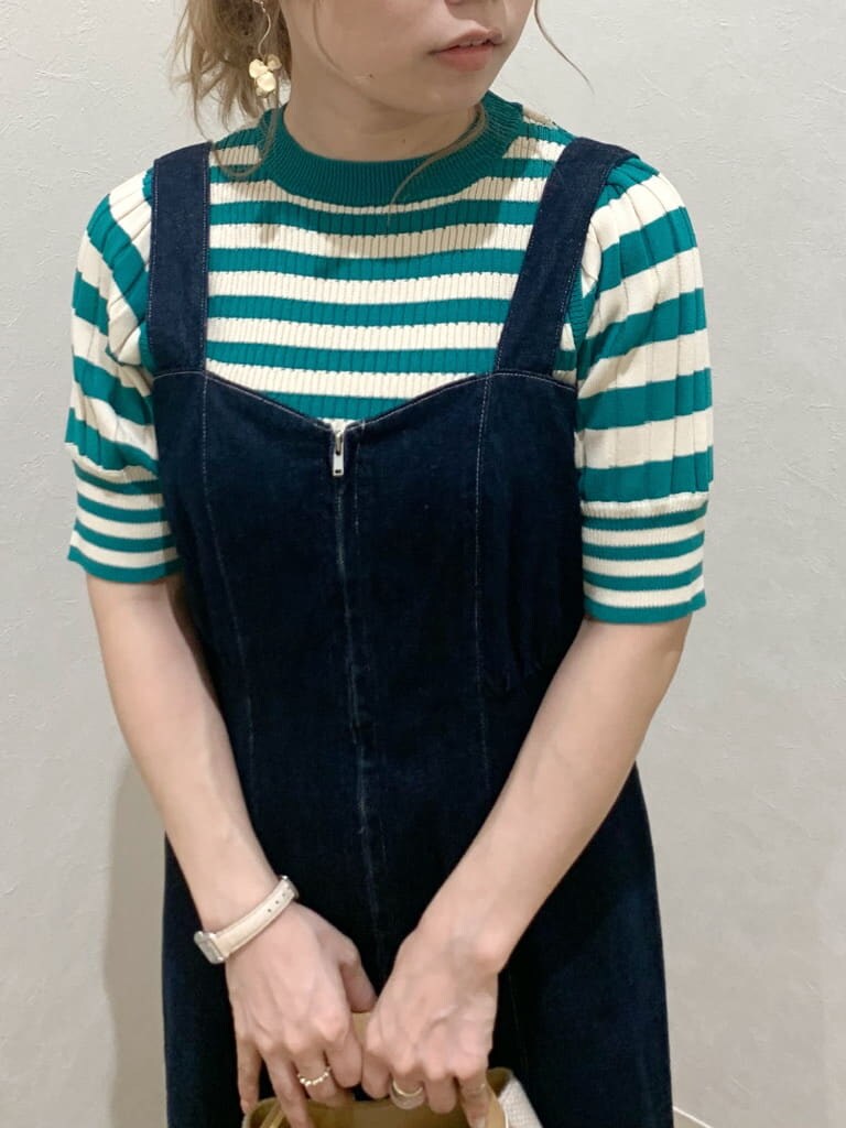 ホワイト系のスニーカー、ブルー系のジャンパースカート、グリーン系のニット/セーターを着用したレディースの春コーディネートの3枚目の写真