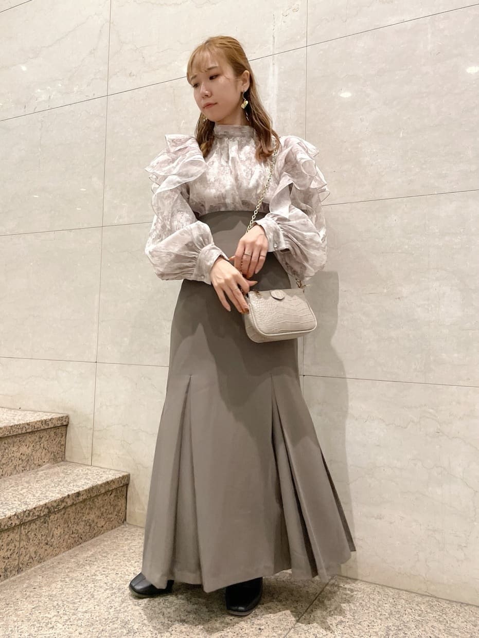 ブラック系のブーツ、ベージュ系のスカート、ベージュ系のシャツ/ブラウスを着用したレディースの秋コーディネートの2枚目の写真