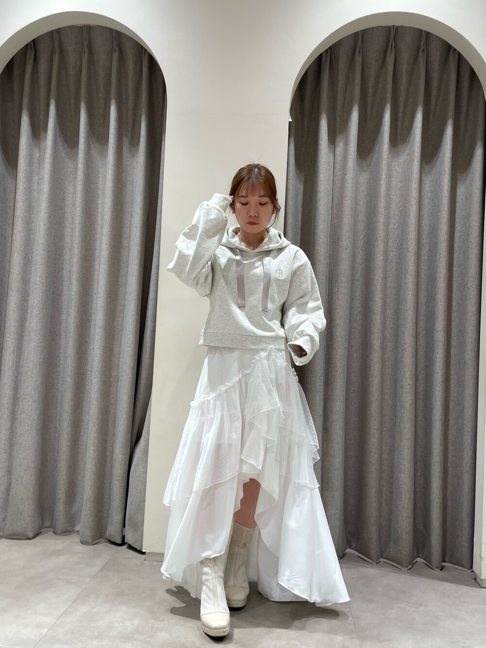 グレー系のパーカー、ホワイト系のスカート、ホワイト系のブーツを着用したレディースの春コーディネートの2枚目の写真