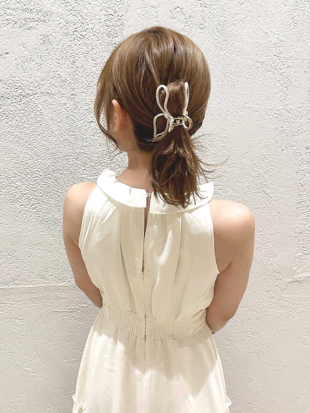 イエロー系のハンドバッグ、ホワイト系のサンダル、ホワイト系のワンピースを着用したレディースの夏コーディネートの7枚目の写真