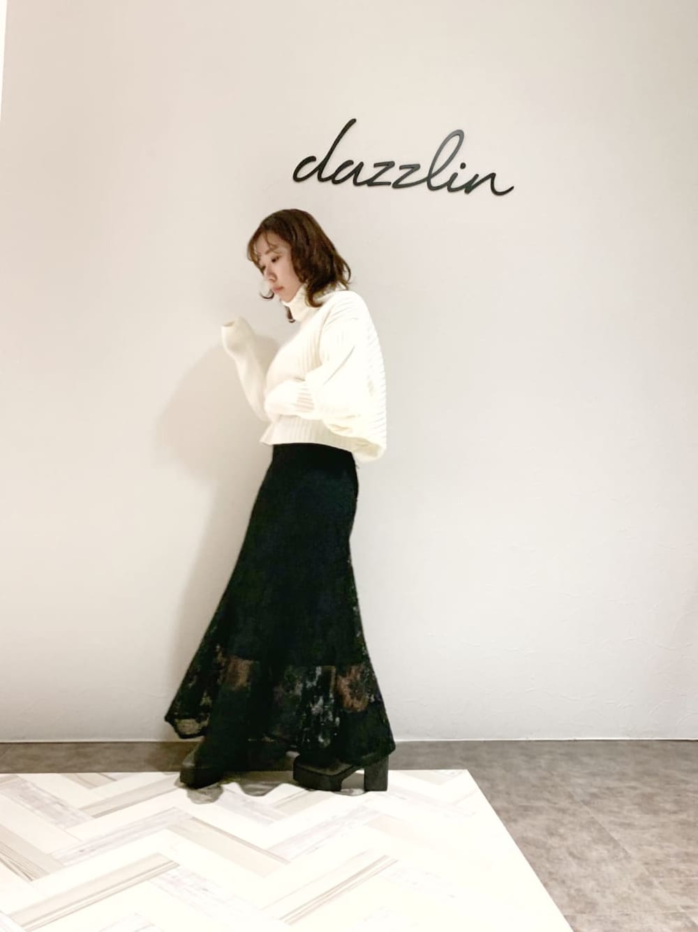 ブラック系のスカート、グレー系のブーツ、ホワイト系のニット/セーターを着用したレディースの秋コーディネートの4枚目の写真