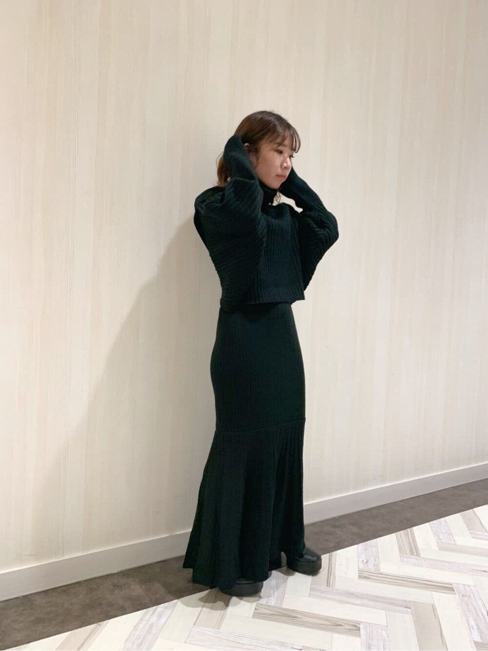 ブラック系のスカート、ブラック系のブーツ、ブラック系のニット/セーターを着用したレディースの秋コーディネートの4枚目の写真