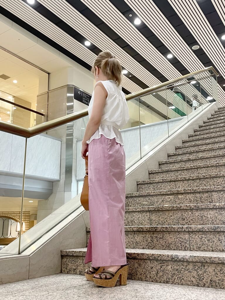 ブラウン系のハンドバッグ、ブラウン系のサンダル、ピンク系のスカートを着用したレディースの夏コーディネートの3枚目の写真