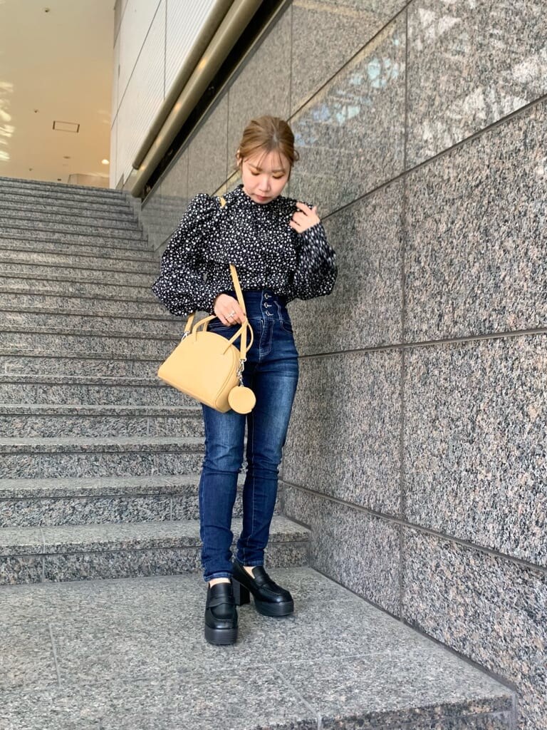 イエロー系のハンドバッグ、ベージュ系のテーラードジャケット、ブラック系のローファーを着用したレディースの冬コーディネートの2枚目の写真