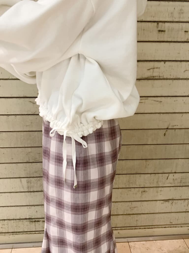 ホワイト系のパーカー、ベージュ系のブーツ、パープル系のスカートを着用したレディースの冬コーディネートの7枚目の写真