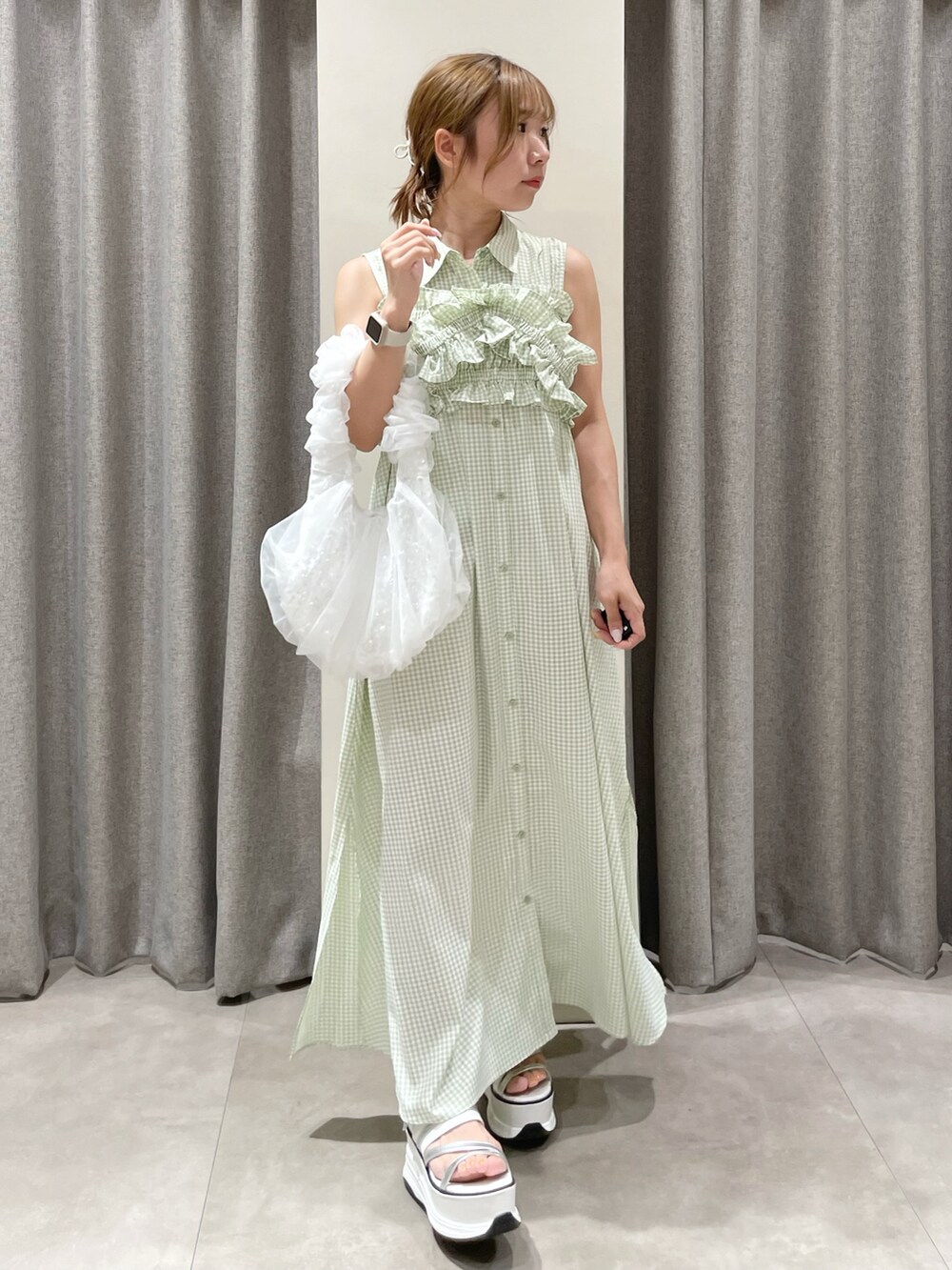 ホワイト系のハンドバッグ、ホワイト系のサンダル、グリーン系のシャツワンピースを着用したレディースの夏コーディネートの3枚目の写真