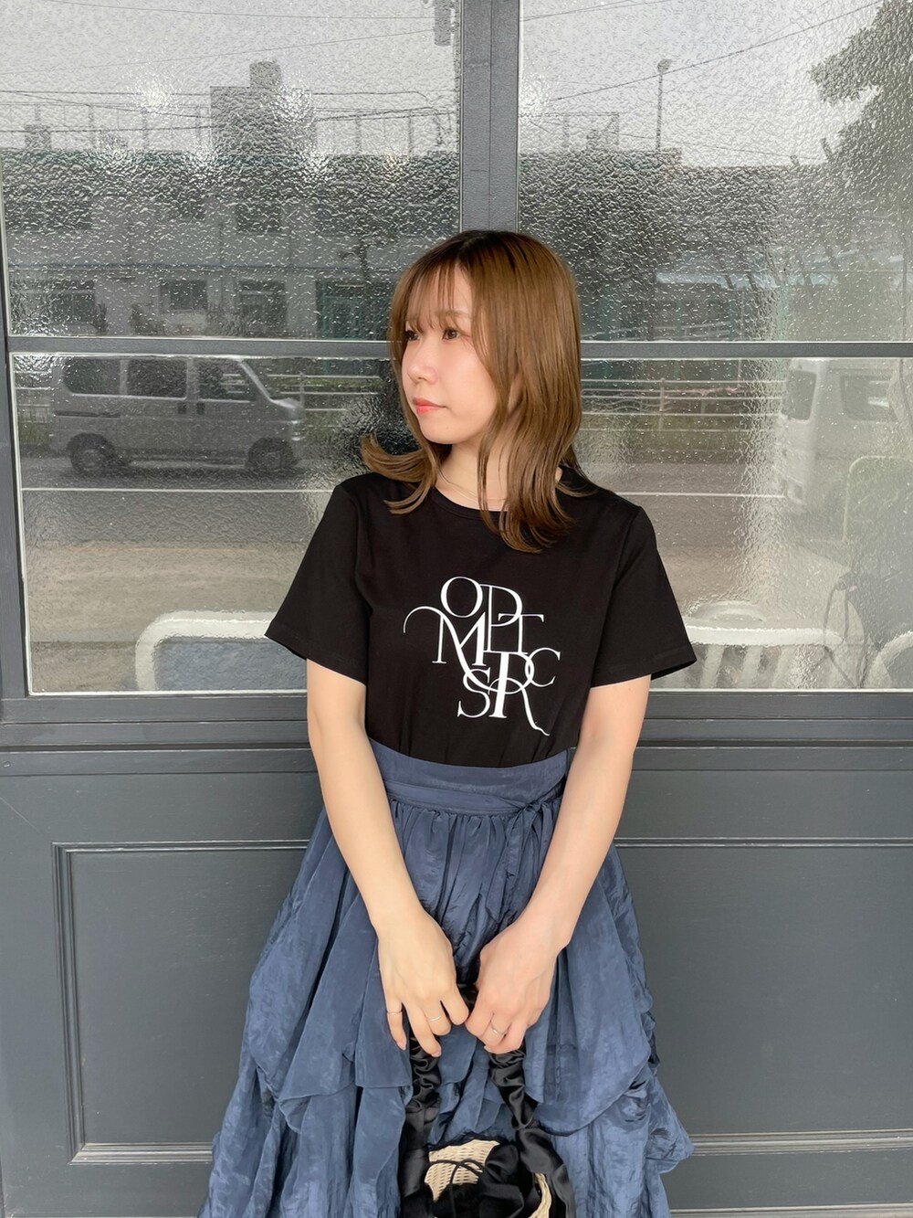 ブラック系のTシャツ/カットソー、ブラック系のかごバッグ、ブルー系のスカートを着用したレディースの夏コーディネートの4枚目の写真