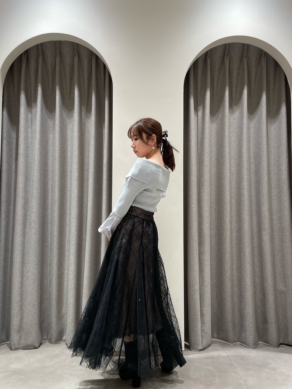 ブラック系のスカート、グレー系のニット/セーター、ブラック系のブーツを着用したレディースの春コーディネートの3枚目の写真