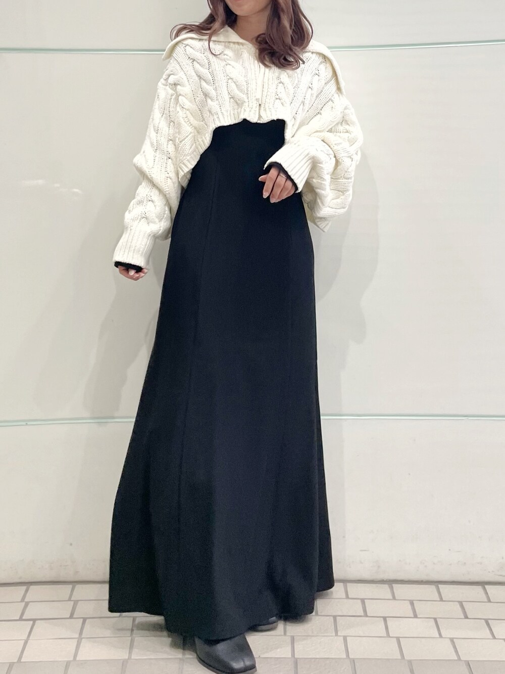 ブラック系のワンピース、ホワイト系のカーディガン/ボレロ、ブラック系のブーツを着用したレディースの秋コーディネートの3枚目の写真