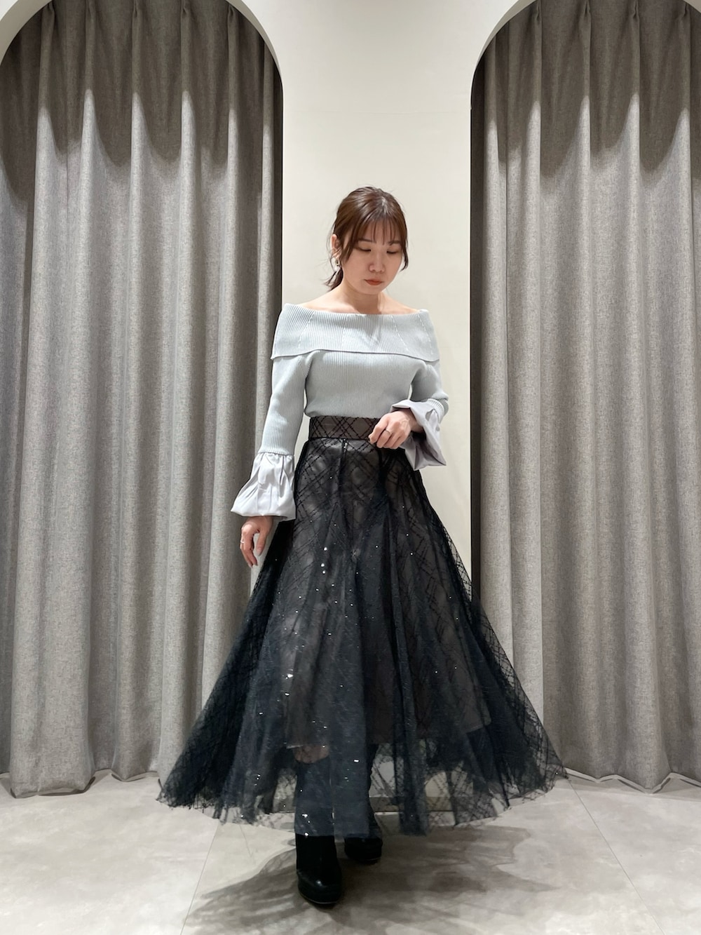 ブラック系のスカート、グレー系のニット/セーター、ブラック系のブーツを着用したレディースの春コーディネートの4枚目の写真