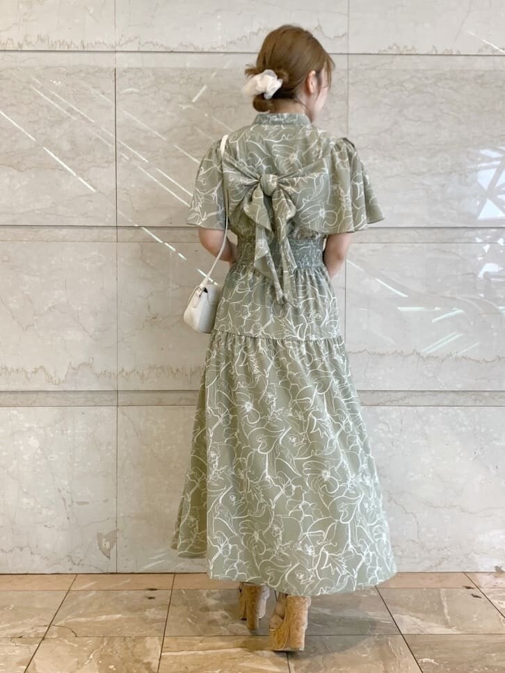 グリーン系のワンピース、ベージュ系のサンダル、ホワイト系のショルダーバッグを着用したレディースの春コーディネートの3枚目の写真