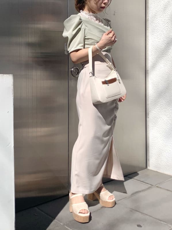 ベージュ系のスカート、グリーン系のTシャツ/カットソー、ホワイト系のサンダルを着用したレディースの春コーディネートの2枚目の写真