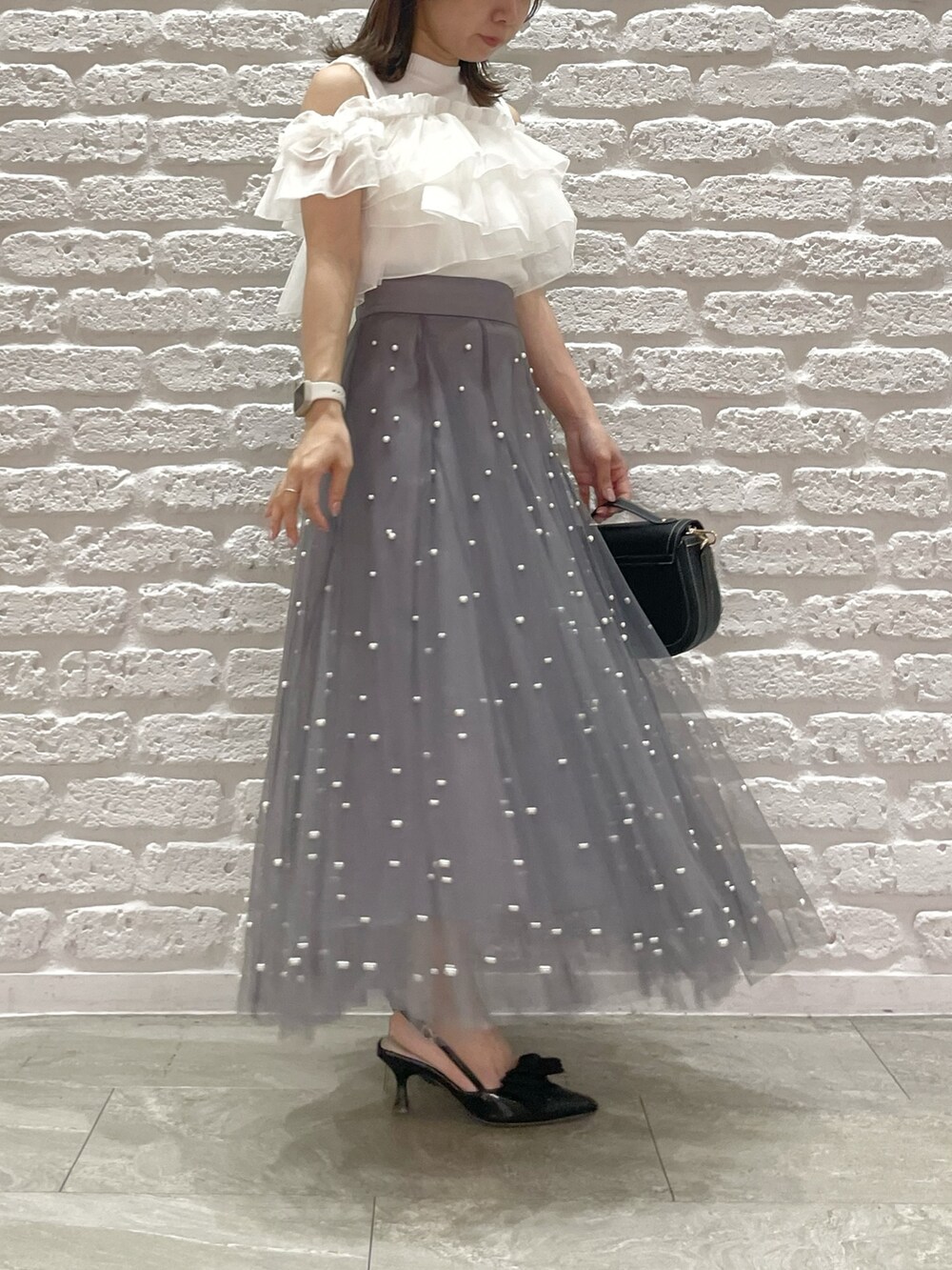 ホワイト系のTシャツ/カットソー、ブラック系のパンプス、ブラック系のハンドバッグを着用したレディースの夏コーディネートの2枚目の写真